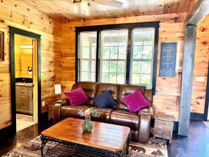 a living room with a leather couch and a table at Luxury 6 BED 5 BATH Mountain Cabin HOT TUB Theater Sleeps 20 IDEAL LOCATION Fireplace KING SUITES Fire Pit GAME ROOM in Sevierville