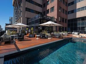 a pool with chairs and umbrellas on a building at Pullman Cape Town City Centre in Cape Town