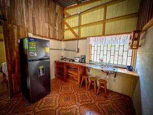 a kitchen with a refrigerator and a counter with stools at Casa Chilamate in Puerto Jiménez +10 photos