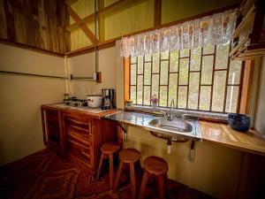 a kitchen with a sink and two stools at Casa Chilamate in Puerto Jiménez