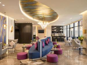 a lobby with a blue couch and pink chairs at Mercure Riyadh Al Anoud in Riyadh