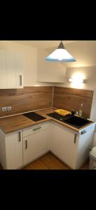 a kitchen with white cabinets and a sink and a light at L'Ephémère in Paroy-sur-Tholon