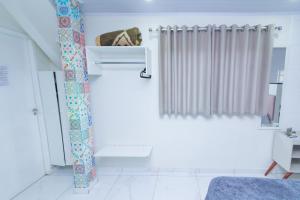 a white bathroom with a shower curtain and a window at Casa do Henrique 2 in Sorocaba