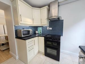a kitchen with white cabinets and a microwave at High Tide House in Waterford