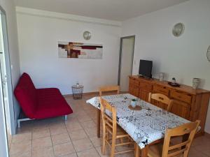 a dining room with a table and a red chair at Gîtes proche lac de chalain in Montigny-sur-lʼAin