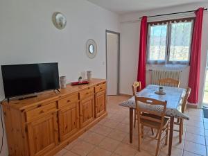 a living room with a television and a table with chairs at Gîtes proche lac de chalain in Montigny-sur-lʼAin