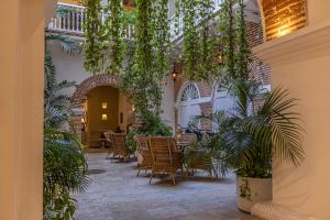 a patio with tables and chairs and plants at Hotel Casa del Gobernador in Cartagena de Indias