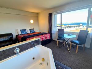 a hotel room with a tub and a bed and a table at Absolute Lake View Motel in Taupo
