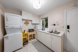 a kitchen with white cabinets and a sink and a refrigerator at Bright Maple Suite in Richmond +19 photos