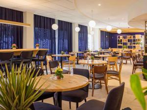 a dining room with tables and chairs and plants at ibis Belfort Danjoutin in Belfort