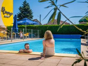 a woman sitting next to a man in a swimming pool at ibis Belfort Danjoutin in Belfort