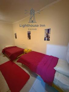 two beds in a room with a light house inn sign at Lighthouse Inn Dahab in Dahab +5 photos