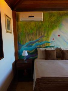 a bedroom with a painting on the wall next to a bed at Pousada Vila de Charme in Lençóis