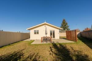 a small white house with a table and a fence at Relax on Rata, Cottage 2 in Twizel