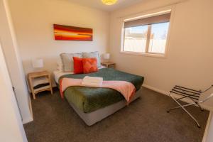 a small bedroom with a bed and a window at Relax on Rata, Cottage 2 in Twizel
