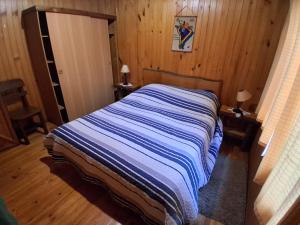 a bedroom with a bed with a blue and white striped blanket at Cabañas Llifén Costanera in llifen