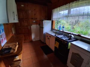 a kitchen with a stove and a refrigerator at Cabañas Llifén Costanera in llifen