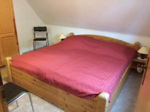 1 dormitorio con cama de madera y colcha roja en Ferienwohnung Büll, en Burg auf Fehmarn
