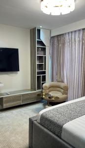 a hotel room with a bed and a chair and a television at NobleStaysTz in Dar es Salaam
