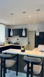a kitchen with blue cabinets and a counter with chairs at NobleStaysTz in Dar es Salaam