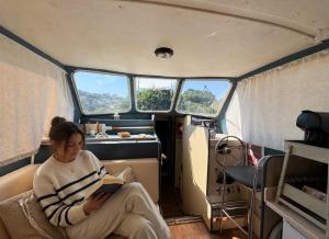 a woman sitting in a van reading a book at Douro Houseboats in Várzea do Douro