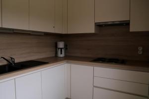 a kitchen with white cabinets and a coffee maker at Apartment Cuypers in Oostduinkerke