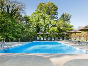 a swimming pool with chairs and umbrellas at Novotel Valence Sud in Valence