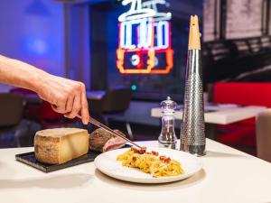 a person cutting into a plate of food on a table at Ibis Milano Centro in Milan