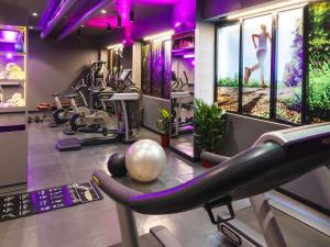a gym with exercise equipment in a room with purple lighting at Ibis Milano Centro in Milan +188 photos