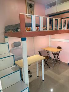 a room with a bunk bed and a desk and tables at Kenjie Apartment in Cordova