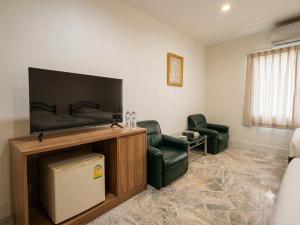 a living room with a flat screen tv and two chairs at โรงแรมลักเซอรี่ Luxury Hotel in Kanchanaburi City