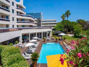 an exterior view of a hotel with a swimming pool at Mercure Hyères Centre Côte d'Azur in Hyères