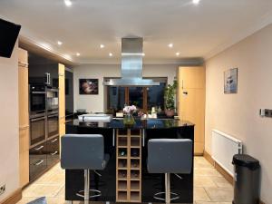a kitchen with a black island with chairs in it at Batty lodge in Cockerham