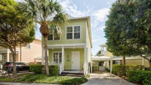 a green house with a palm tree in front of it at Pristine Islamorada Pool Home with Ocean View and Dockage in Islamorada