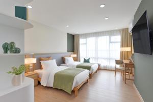 a hotel room with two beds and a flat screen tv at SENS Hotel Nonthaburi Bangbuathong in Nonthaburi