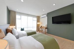a hotel room with two beds and a flat screen tv at SENS Hotel Nonthaburi Bangbuathong in Nonthaburi