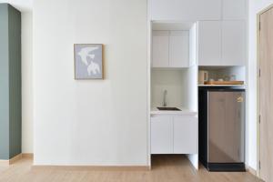 a kitchen with white cabinets and a refrigerator at SENS Hotel Nonthaburi Bangbuathong in Nonthaburi