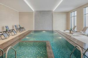 a swimming pool in a room with chairs and a table at Element by Marriott Al Qassim in Buraydah