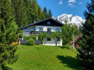 a large white house with a mountain in the background at Landhaus Herz der Tauern in Mallnitz
