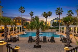 a pool with chairs and palm trees in a resort at Gulf View Beach Home with Pool in Gulf Shores