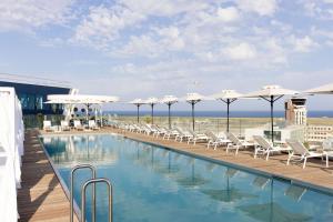 a swimming pool with white chairs and umbrellas at Sheraton Nice in Nice