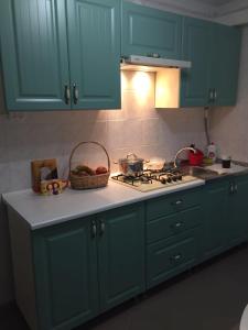 a kitchen with blue cabinets and a stove with a basket of fruit at Holiday house near sea on Lvovskaya in Odesa