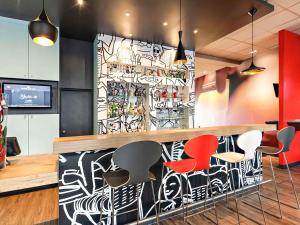 a restaurant with a bar with colorful chairs at Ibis Agen Centre - Rénové en 2026 in Agen