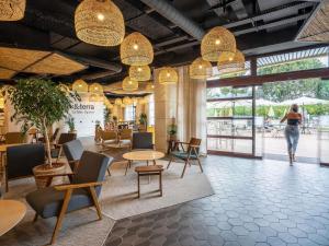 a woman walking through a lobby with tables and chairs at Mercure Cannes Mandelieu in Cannes
