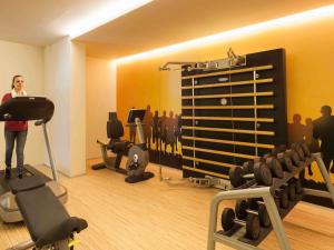a woman standing in a gym with weights at Novotel Setubal in Setúbal