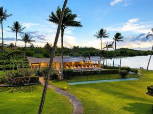 a house with palm trees in front of it at Wavecrest - 4BR Condos - Sleeps 12 in Kaunakakai