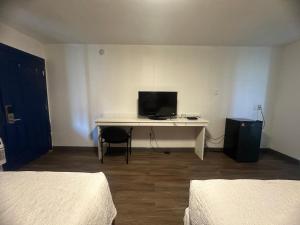 a room with two beds and a desk with a television at Union Avenue Motel in Portland