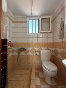 a bathroom with a toilet and a window and a sink at Komi Seaside Living in Kómi +18 photos