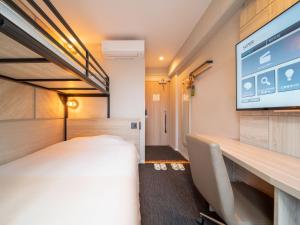 a room with a bed and a flat screen tv at Super Hotel Tottori Ekimae in Tottori
