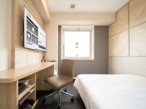 a hotel room with a bed and a desk and a television at Super Hotel Tottori Ekimae in Tottori